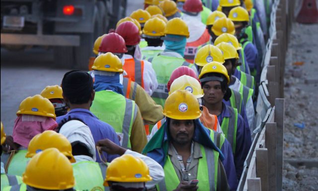 Workers at the 6am change of shift on a 2022 World Cup construction site.