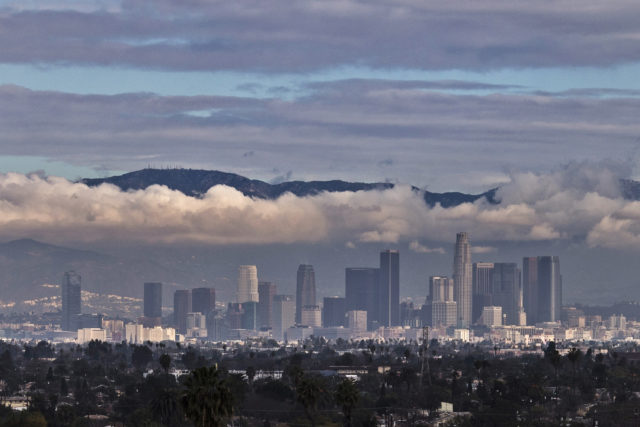 The San Gabriel Mountains are seen in the background during cloud cover over the Los Angeles skyline